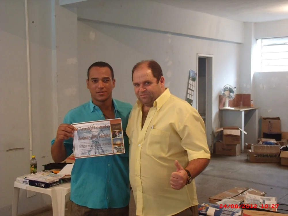 Claudio Moraes ao lado de um aluno com certificado, em registro de sua trajetória no ensino de elétrica